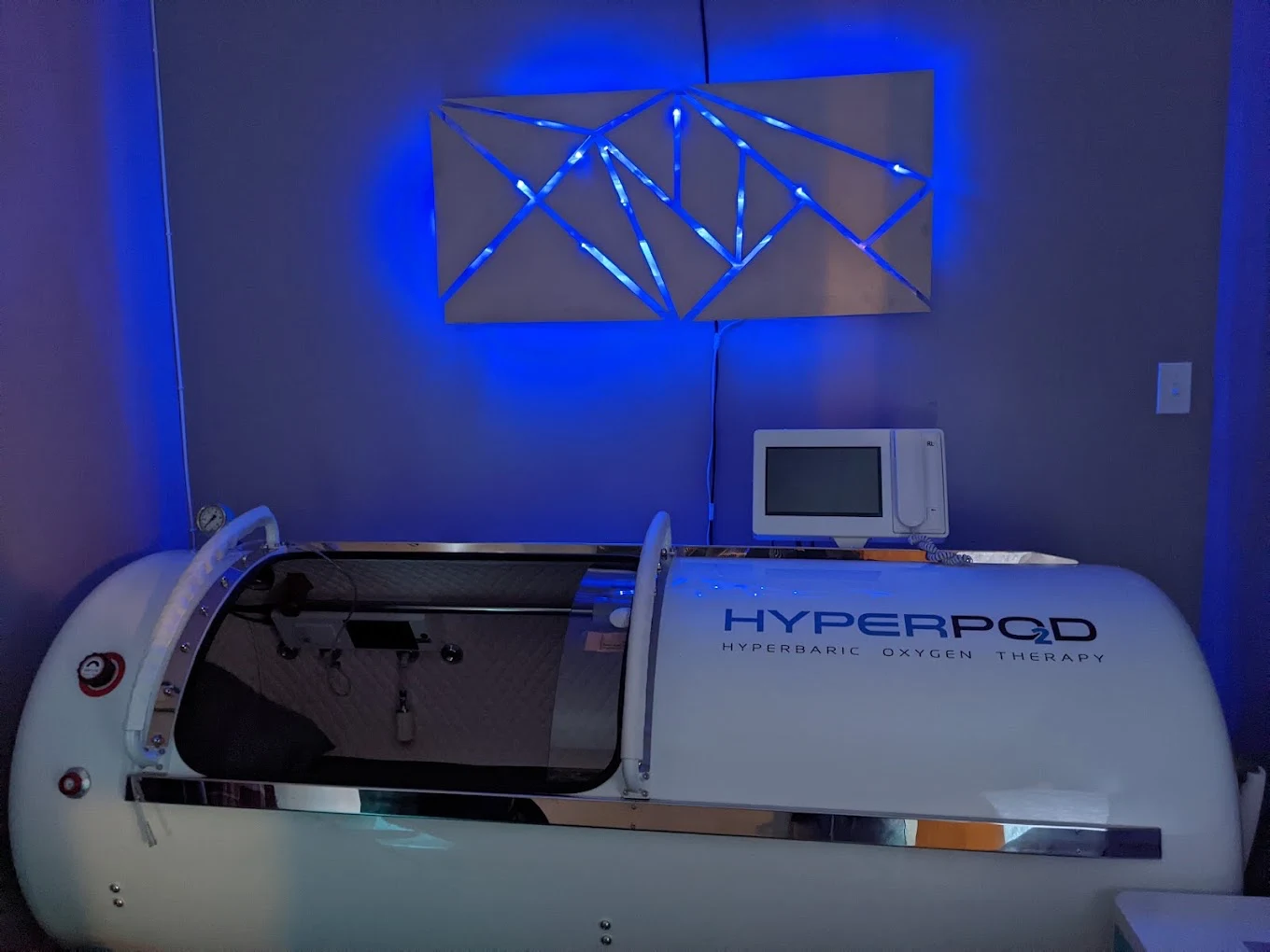 The Hyperpod hyperbaric chamber under soft blue light at Serenus Float & Wellness in Bloomington, Indiana